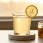 Glass of lemon baking soda water with honey on a concrete coaster — the honey variation is palatable and doesn't affect the core chemistry
